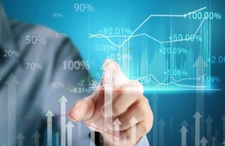 A person in a business suit uses a transparent digital screen to draw or interact with financial graphs and rising line charts, representing growth and analysis.