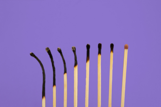 Eight matches in a row against a purple background; five on the left are burnt and bent, gradually becoming less burnt, while the last on the right is unburnt and straight.