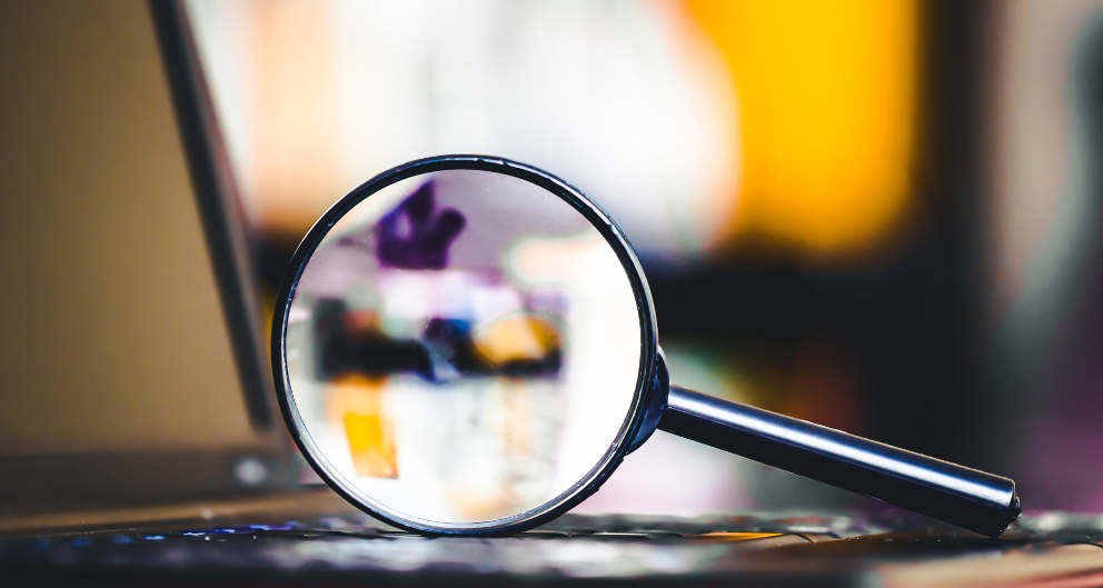 An up-close shot of a magnifying glass balanced on a computer keyboard
