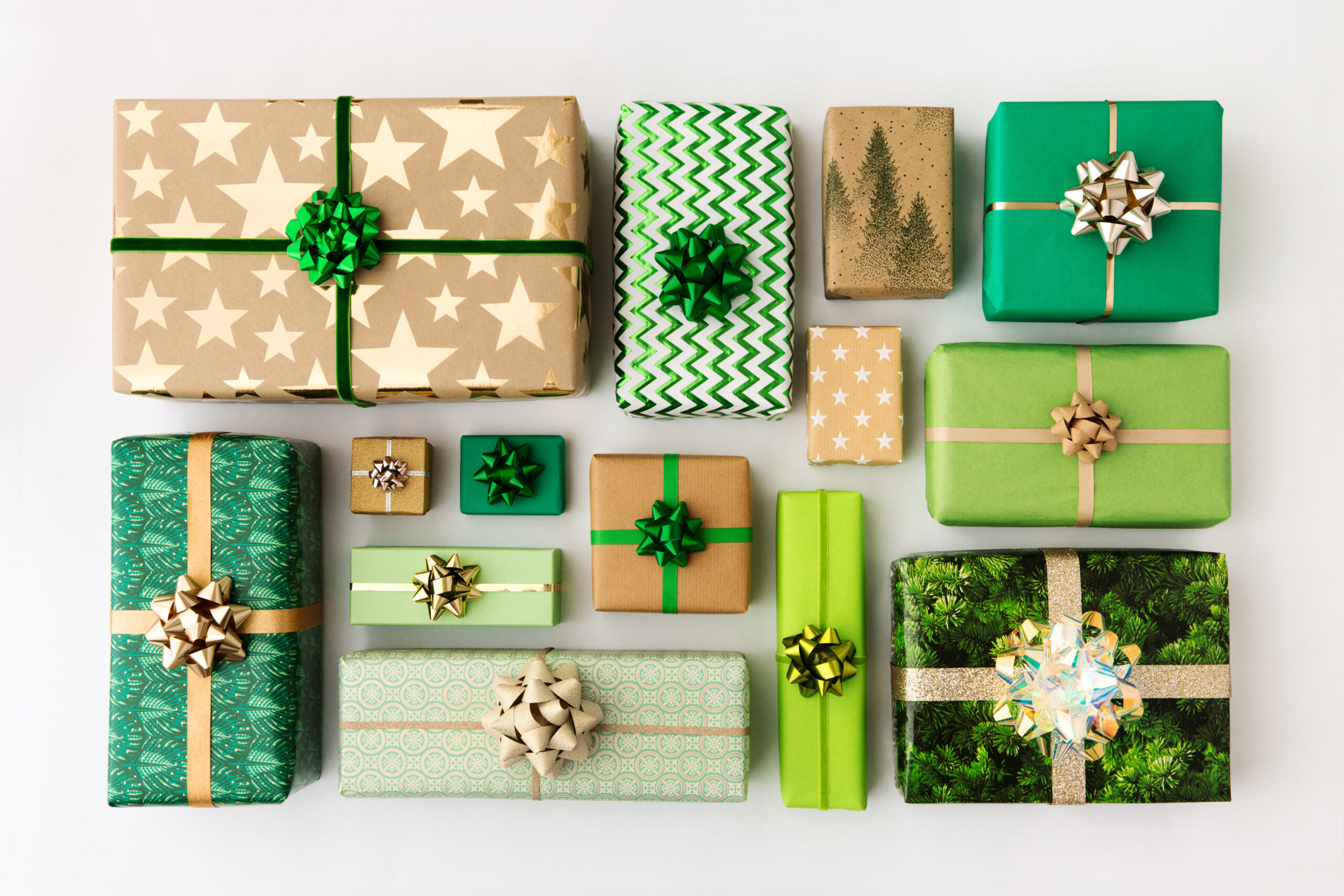 A collection of neatly wrapped gifts in green, gold, and brown paper with various patterns, each topped with a shiny bow, arranged in a grid on a white background.